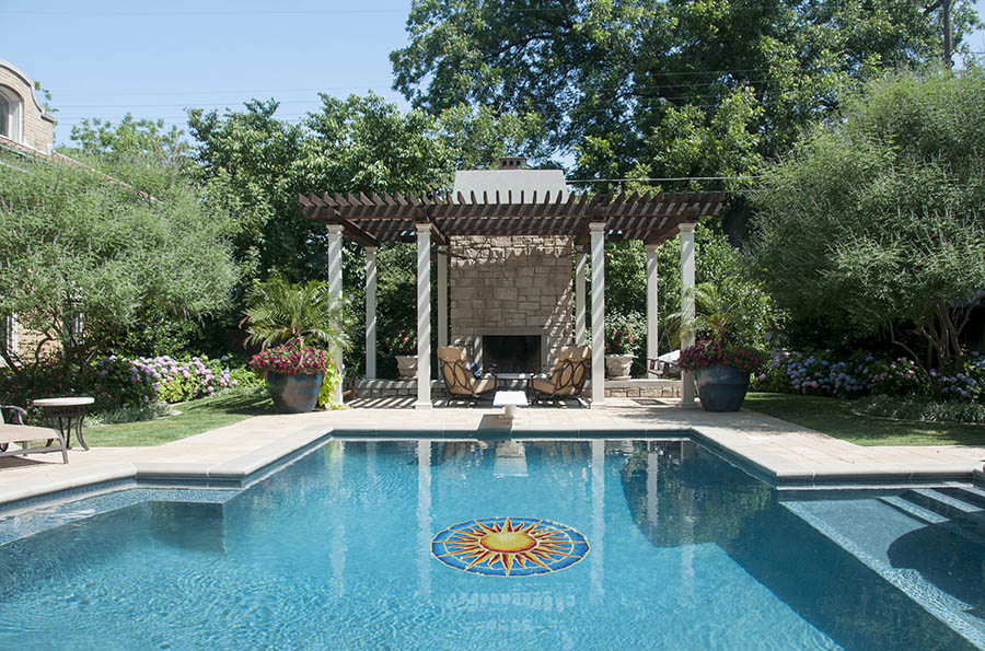Pool with decorative mosaic, lounge chairs, and a gazebo in a garden setting.